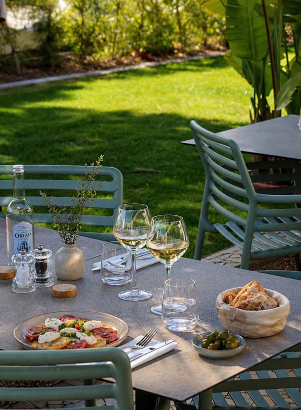 Restaurant Le Kallisté à Hyères, terrasse près de la plage de l’Ayguade Terrasse du restaurant Le Kallisté à l’Ayguade à Hyères avec table dressée, plats et ambiance jardin proche de la plage